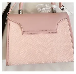 Detail of pink handbag featuring snake pattern texture and delicate lace bow decoration