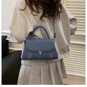 Détail d'un sac bandoulière en cuir bleu foncé avec fermoir doré sur un modèle