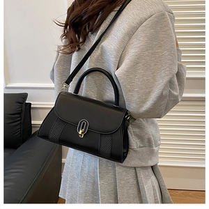 Détail du sac bandoulière noir avec texture tissée en V et fermoir doré rotatif