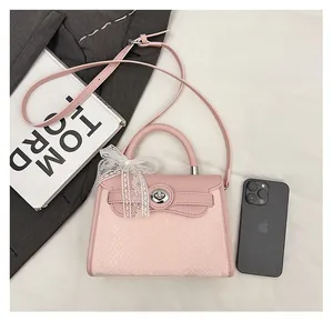Pink croc-embossed handbag detail with lace bow, silver twist lock, and size comparison
