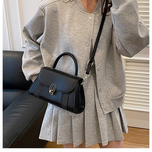 Détail du sac à main noir avec boucle en U dorée et panneau à texture tissée