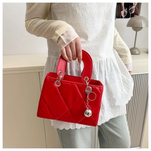 Detail of red quilted handbag with silver hardware and metallic ball charm accessory
