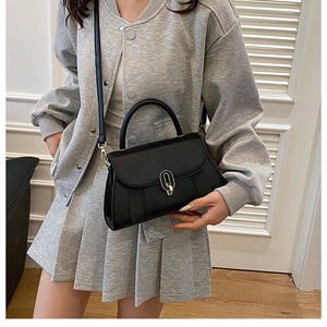 Gros plan d'un sac bandoulière en cuir noir avec boucle métal et détails tissés latéraux
