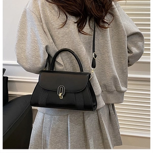 Détail du sac en cuir noir mat avec motif en losanges et fermoir rotatif doré élégant