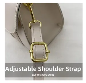 Détail d'une bandoulière en cuir réglable avec boucle en métal doré sur un sac beige