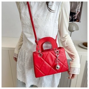 Rote Stepptasche mit silbernem Kugelanhänger und elegantem Tragegriff im Detail