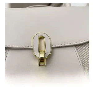 Détail de la boucle dorée ovale et du tissu beige texturé sur un sac à bandoulière
