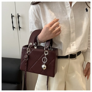Detail der burgunderroten Stepptasche mit silbernen Beschlägen und Kugelanhänger