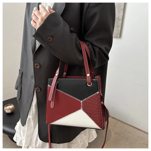Detail der Farblock-Ledertasche mit Webstruktur, getragen von Model im schlichten Stil