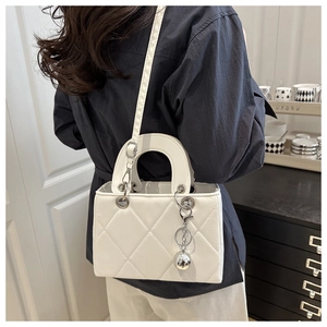 Detail of white quilted crossbody bag with silver sphere charm and leather strap