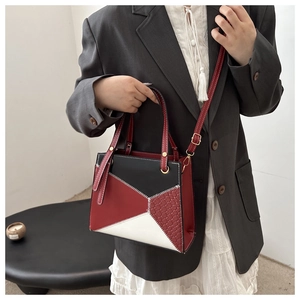 Detail of contrast color handbag with red woven texture side panel and leather shoulder strap