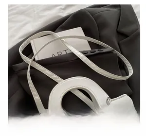 Detail of white quilted handbag with round handle and adjustable strap on blazer