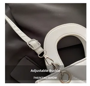 Detail of adjustable silver buckle and metal hook on white leather shoulder strap