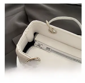 Macro shot of smooth silver zipper and fine quilting on a white leather handbag
