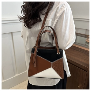 Detail of color-block leather bag with crocodile texture and white contrast stitching