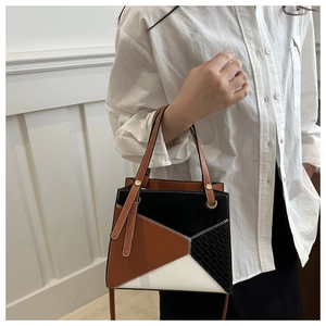 Close-up of geometric patchwork handbag with crocodile texture and white stitching details