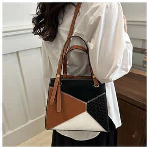 Detail of color-block tote bag with animal embossed texture and contrast stitching