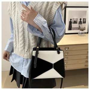 Detail of minimalist black and white geometric handbag with contrast stitching and gold ring