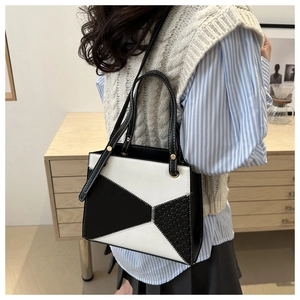 Detail of black and white geometric leather tote bag featuring woven texture and gold rings