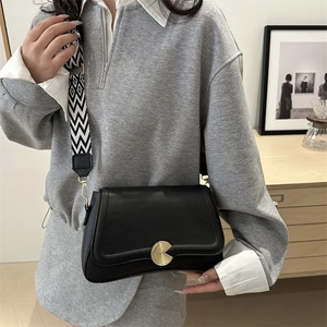 Minimalist black lychee leather crossbody bag with geometric woven wide shoulder strap