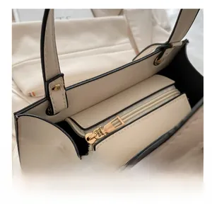 Detailansicht der cremefarbenen Ledertasche mit goldenem Reißverschluss und schwarzer Kante