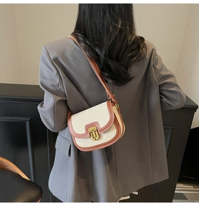 Close-up of saddle bag with beige canvas and brown leather trim on a gray blazer