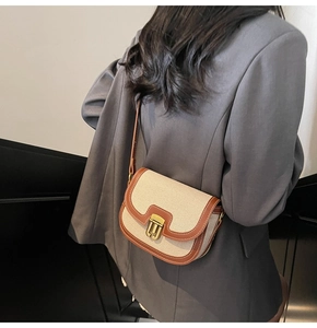 Retro canvas saddle bag with brown leather trim worn as a stylish crossbody on a grey blazer