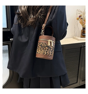 Model wearing a vintage leopard print cylindrical bucket bag with brown leather accents
