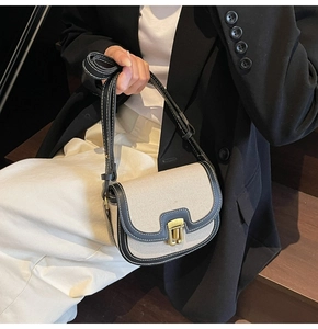 Detail of canvas saddle bag with black leather trim and vintage gold clasp closure