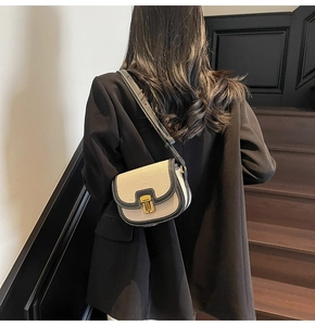 Detail of canvas saddle bag featuring black leather trim and golden metal push-lock
