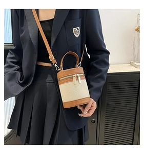 Detail of canvas bucket bag with brown leather trim shown on blue blazer outfit