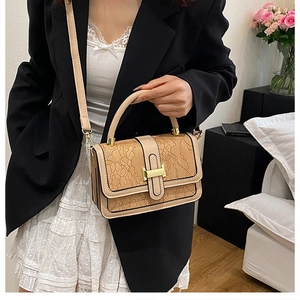 Close-up of beige embossed PU leather bag with lace texture and H-shaped metal clasp