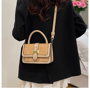 Detail of beige lace-textured crossbody bag with golden rectangular turn-lock closure