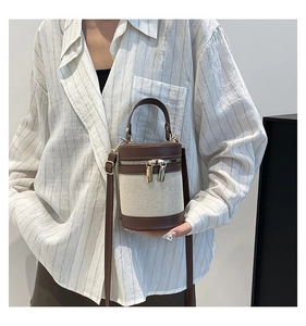 Detail of linen and brown leather patchwork bucket bag with gold hardware and top handle