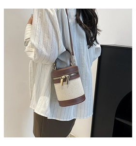 Detail of color-block bucket bag with canvas body, leather trim and gold hardware
