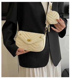 Detail of cream chevron quilted crossbody bag with a round coin pouch and gold twist lock