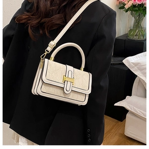 Detail of cream crossbody bag featuring elegant lace texture and gold hardware on model