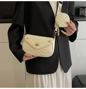 Detail of cream quilted crossbody bag with small round coin purse and wide shoulder strap