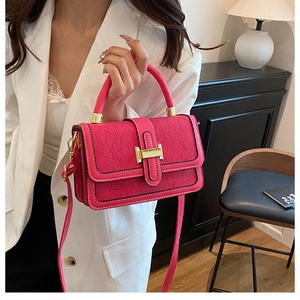 Detail of rose pink PU leather handbag with floral lace embossing and gold H-buckle