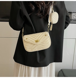Detailed view of beige wavy quilted crossbody bag with small round coin purse on wide strap