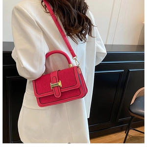 Detail of rose red square bag featuring floral embossing and gold metallic buckle