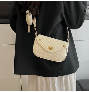 Detail of cream chevron quilted crossbody bag with small round coin purse and gold clasp