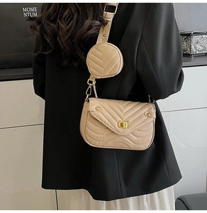Close-up of beige quilted leather crossbody bag with golden twist lock and wide strap