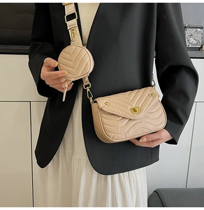 Detail of beige crossbody bag featuring V-shaped stitching and wide textile strap