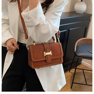 Close-up of vintage brown embossed leather handbag with golden H-shaped metal buckle detail