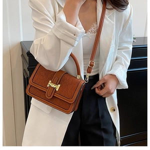 Close-up of caramel brown handbag featuring laser-cut floral texture and golden H buckle
