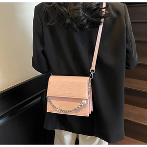 Close-up of pink croc-embossed bag featuring silver chain and elegant pearl detailing