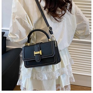 Detail of black textured leather bag with white contrast stitching and golden H-clasp