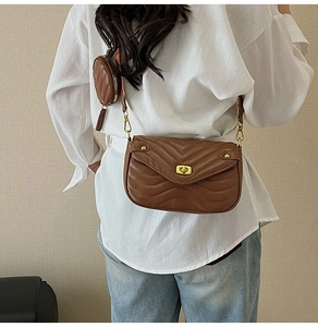 Detailed view of brown quilted crossbody bag with wide strap and round coin purse attachment