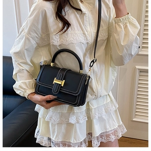 Detail of black structured crossbody bag featuring white stitching and gold H-clasp hardware